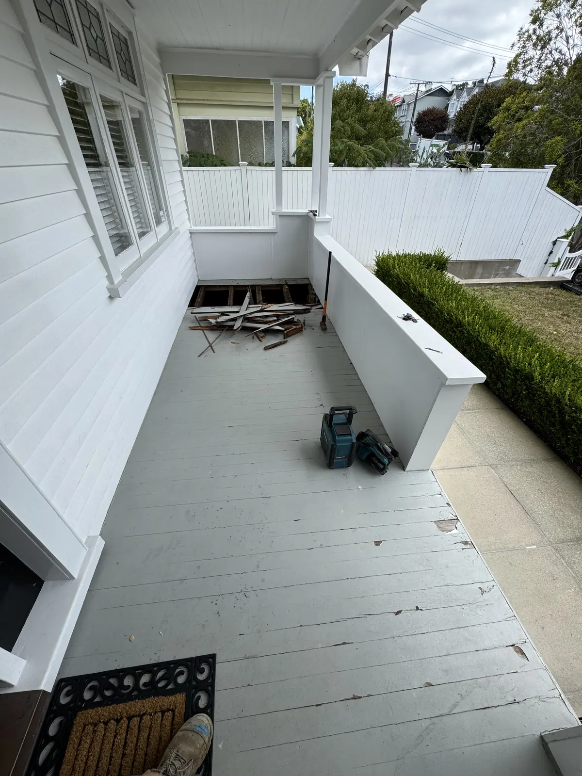 Old painted deck beside a white villa with worn paint and boards pulled up