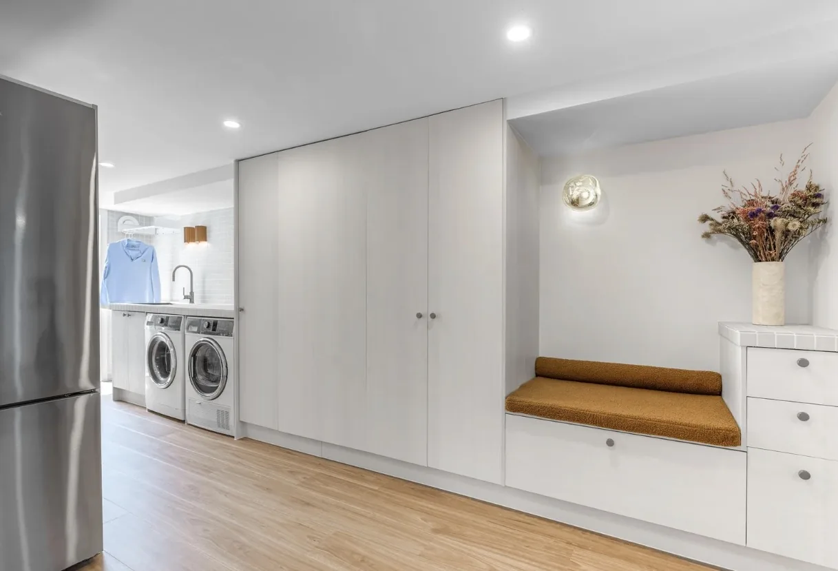 Laundry and storage wall with white cabinetry and a built-in cushioned bench seat