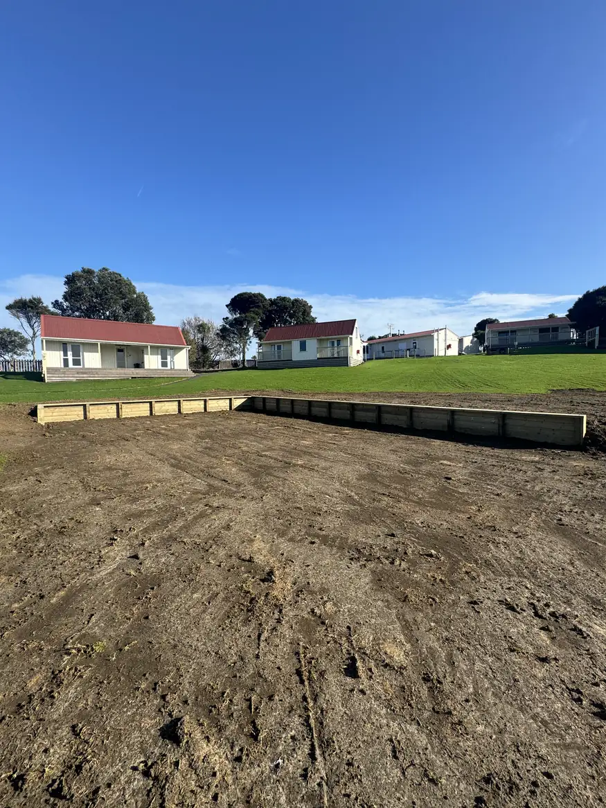 Levelled bare section with a timber edge along the back and houses on the rise behind