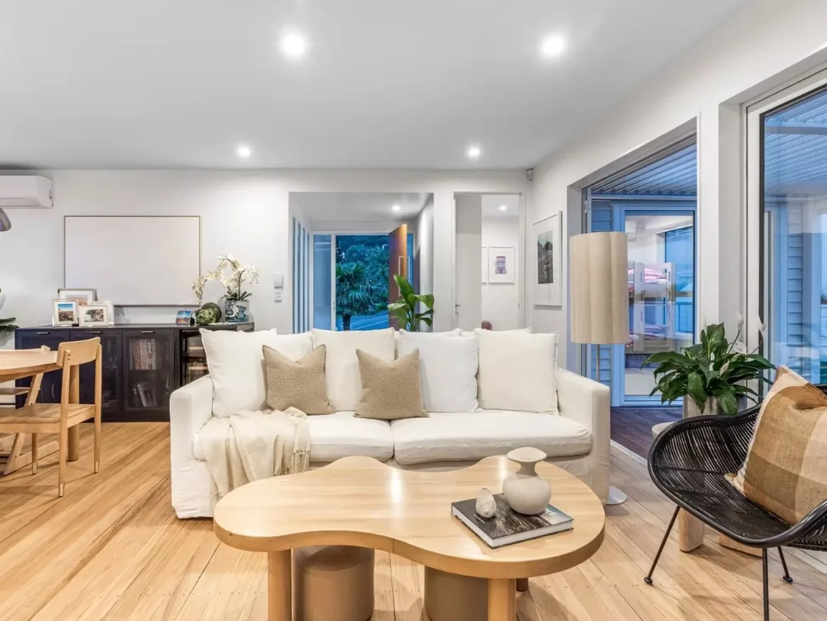 Warm-lit living room with timber floor and doors opening to a covered deck