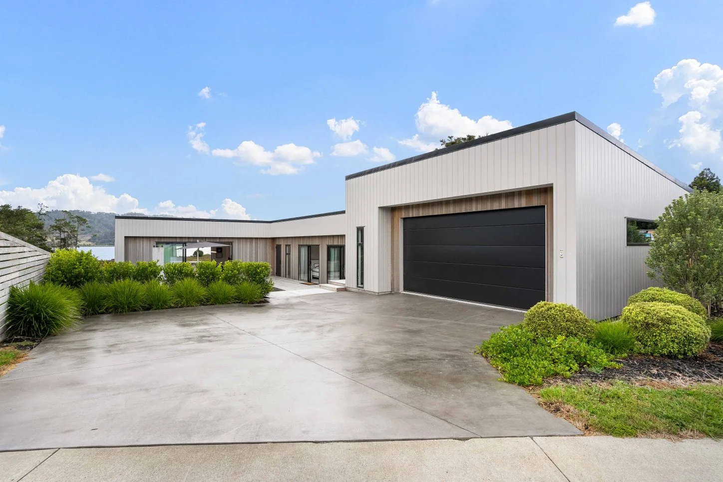 Modern home with a garage, concrete driveway and planted garden