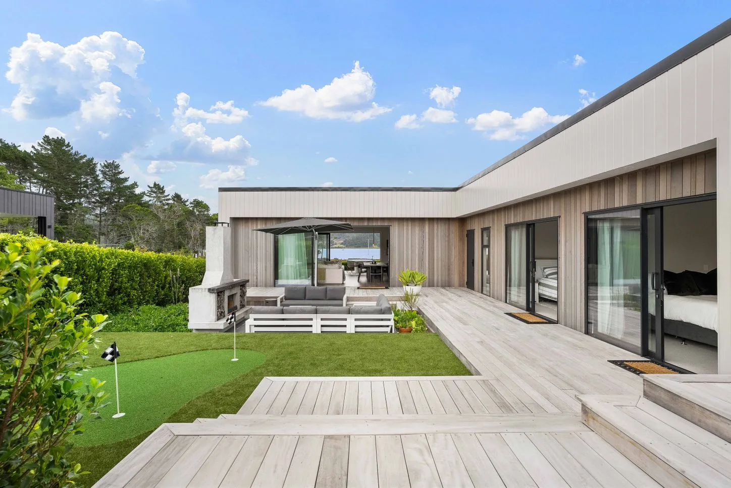 Timber-clad home with a pale deck, lounge and putting green